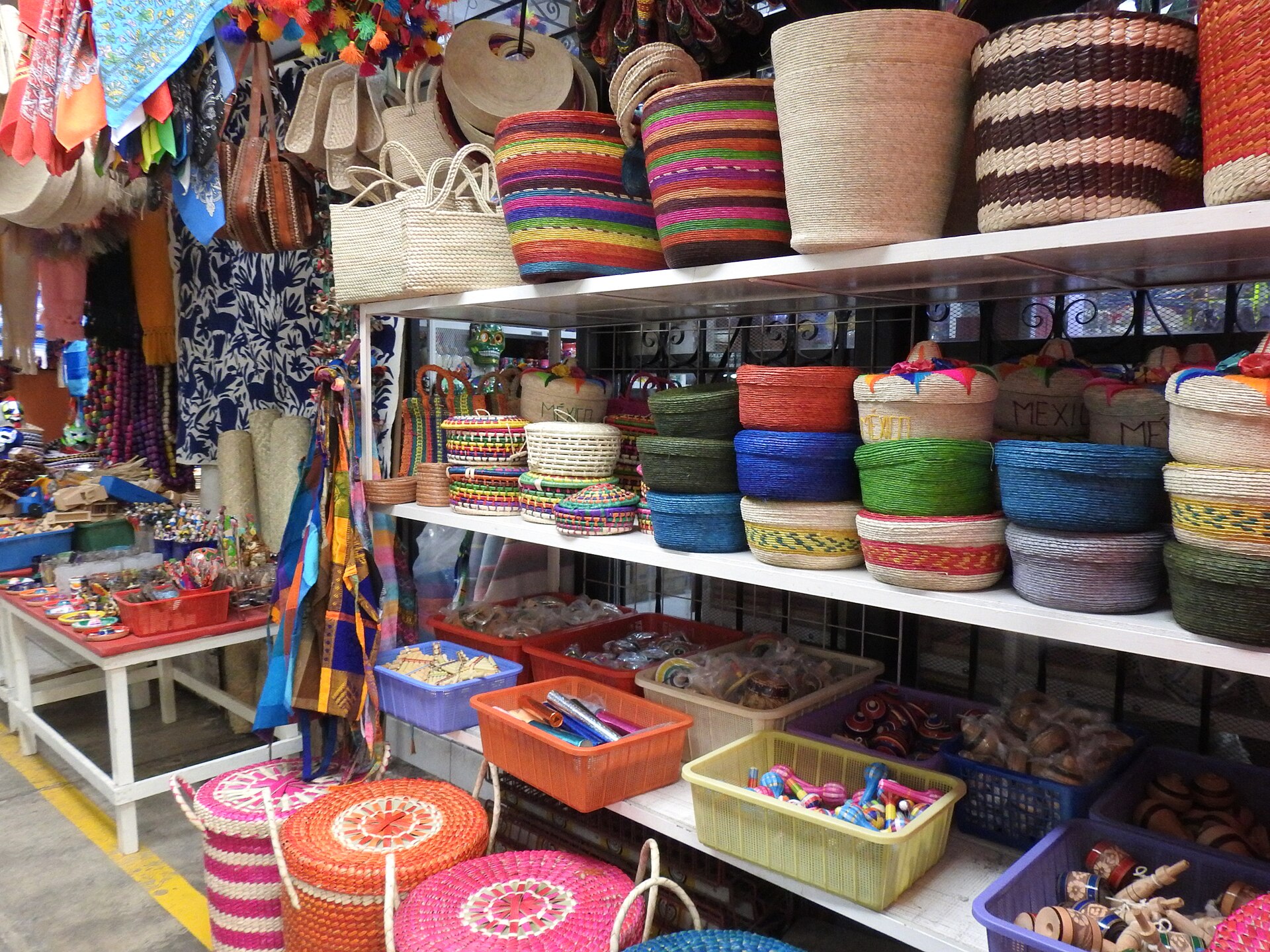 A craft market stall with shelves of brightly coloured woven palm baskets, textiles, wooden toys and painted souvenirs