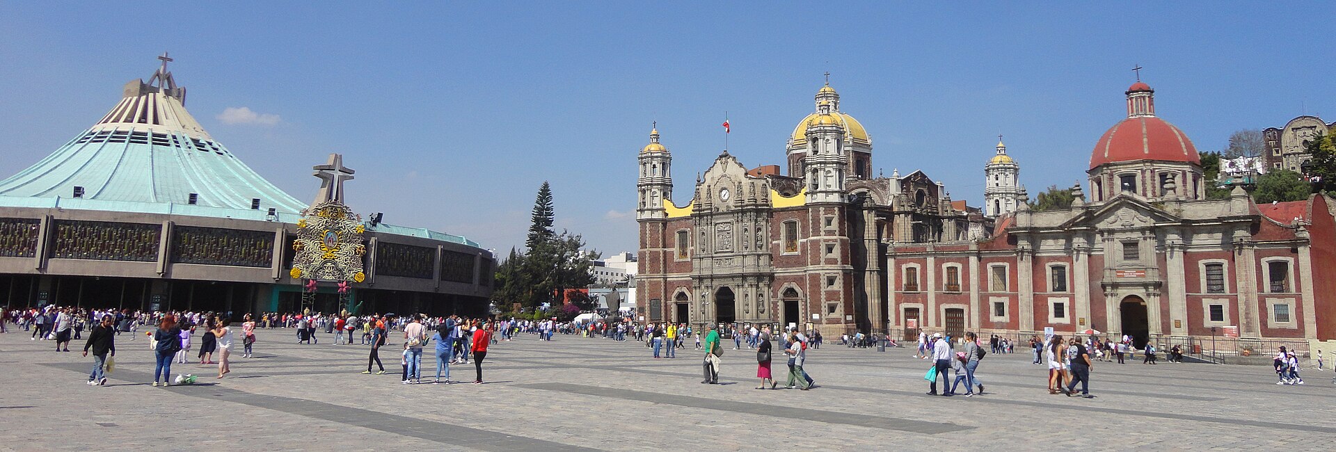The wide paved atrium of the Basilica of Guadalupe with the modern conical green-roofed basilica on the left and the older colonial churches on the right