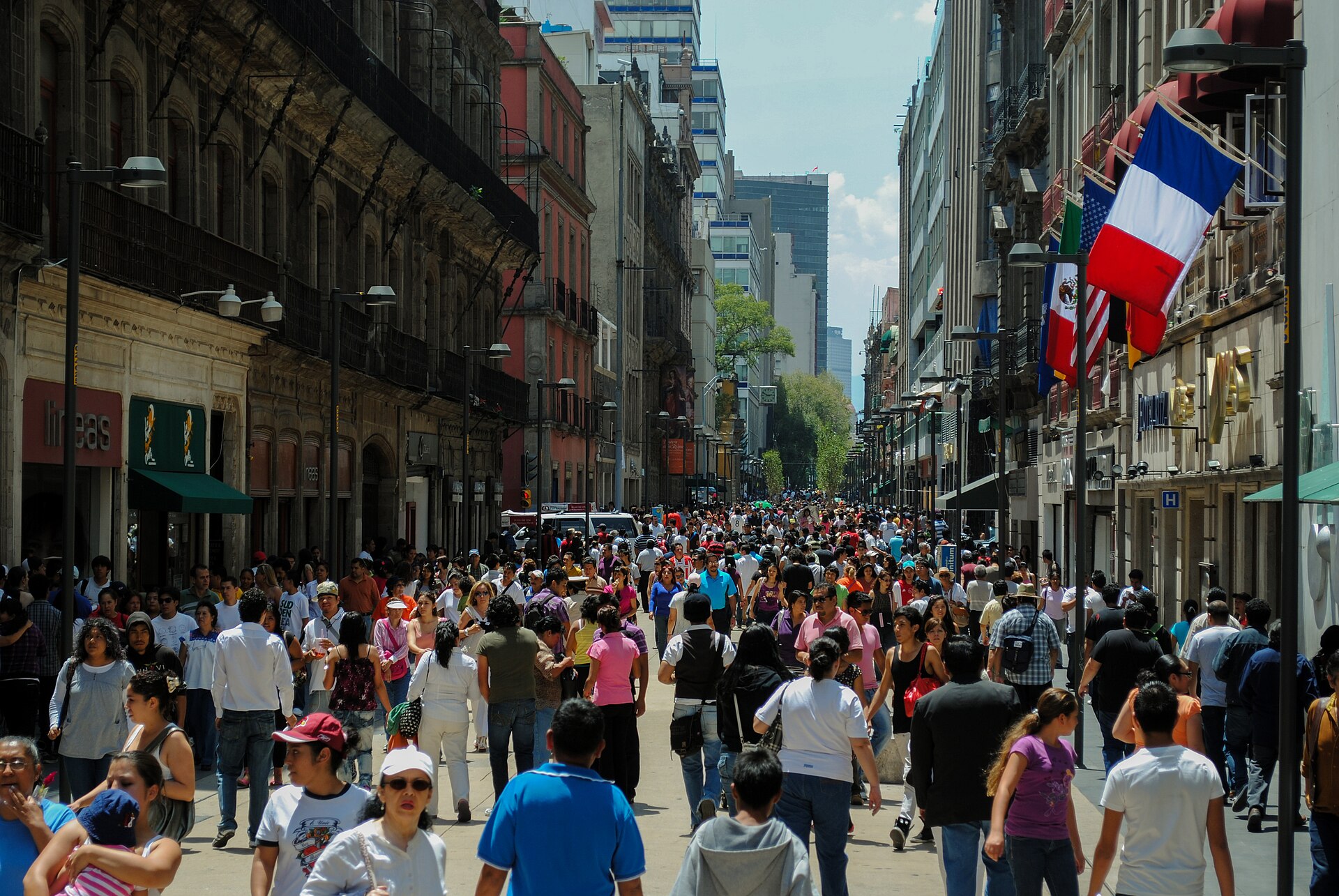Calle Madero in the historic centre of Mexico City filled end to end with people walking in daylight between historic buildings