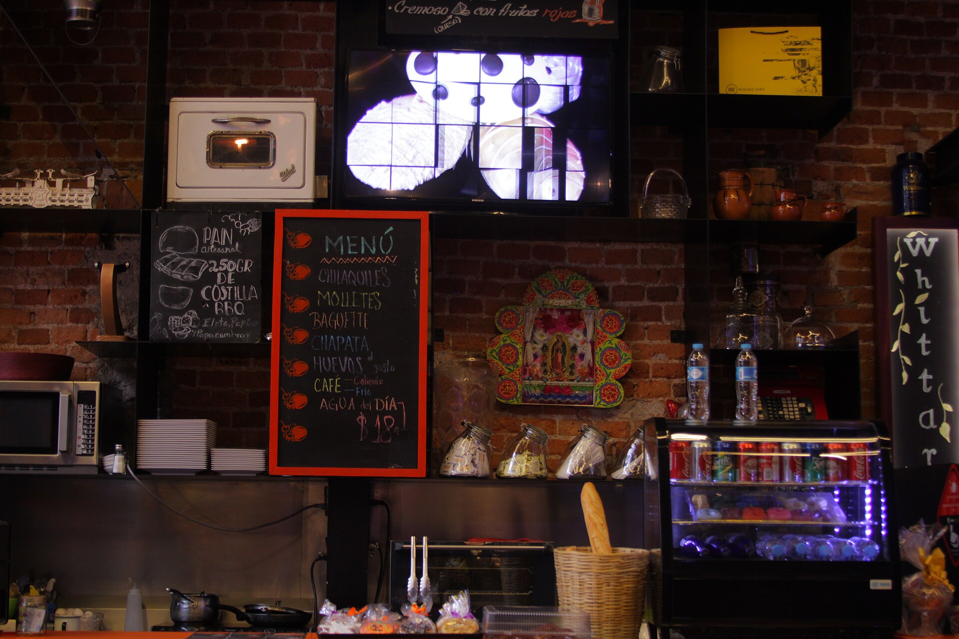 A food stall inside Mercado Roma in Mexico City with a handwritten chalkboard menu listing chilaquiles, molletes and coffee