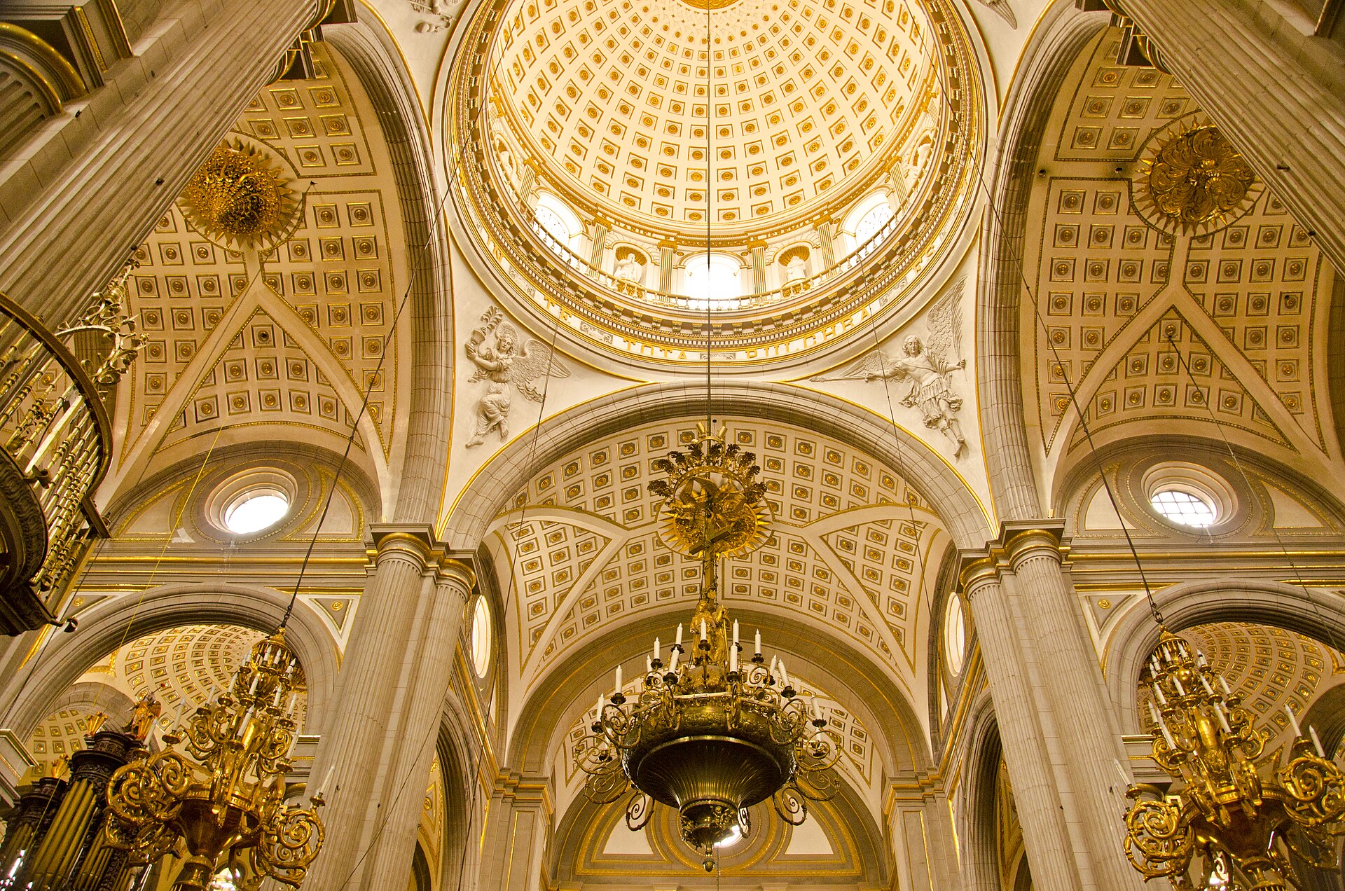 The gilded coffered dome and vaults above the crossing of Puebla Cathedral, with chandeliers hanging from the arches